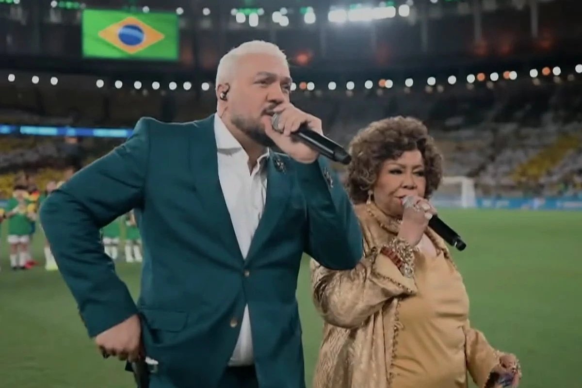 Belo e Alcione são detonados após cantar hino em amistoso da Seleção